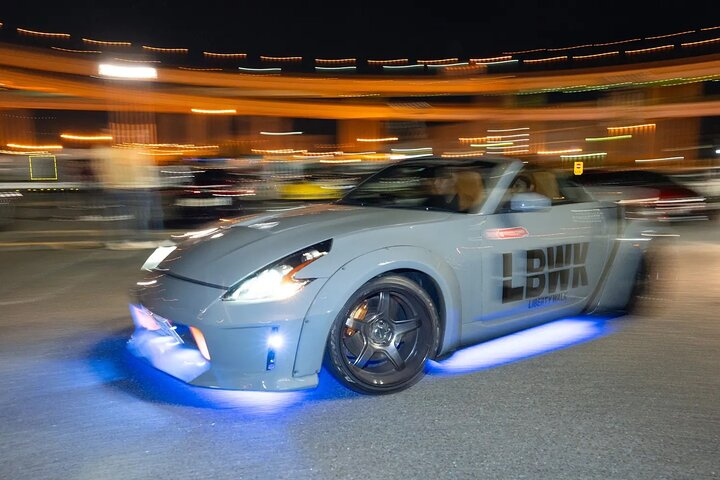 Liberty Walk Nissan 350Z Roadster mit blauer Unterbodenbeleuchtung nachts an der Daikoku PA