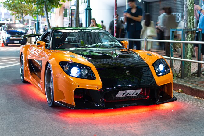 Orange-schwarzer Veilside RX-7 wie Hans Tokyo-Drift-Auto, nachts auf einer Straße in Tokio geparkt